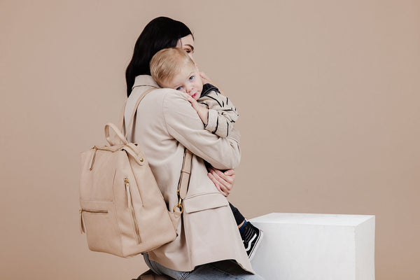 Woman holding toddler with stylish diaper bag