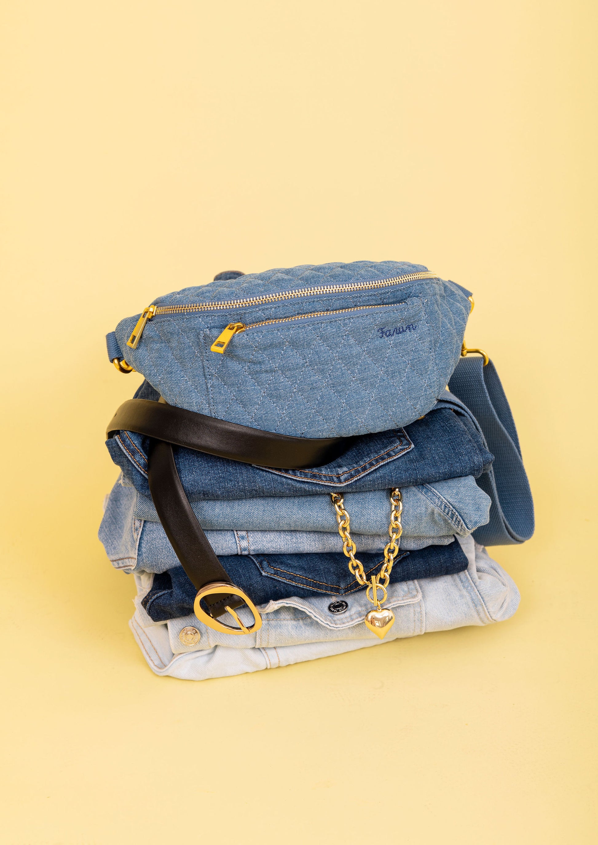 Stack of blue jeans with accessories on a yellow background