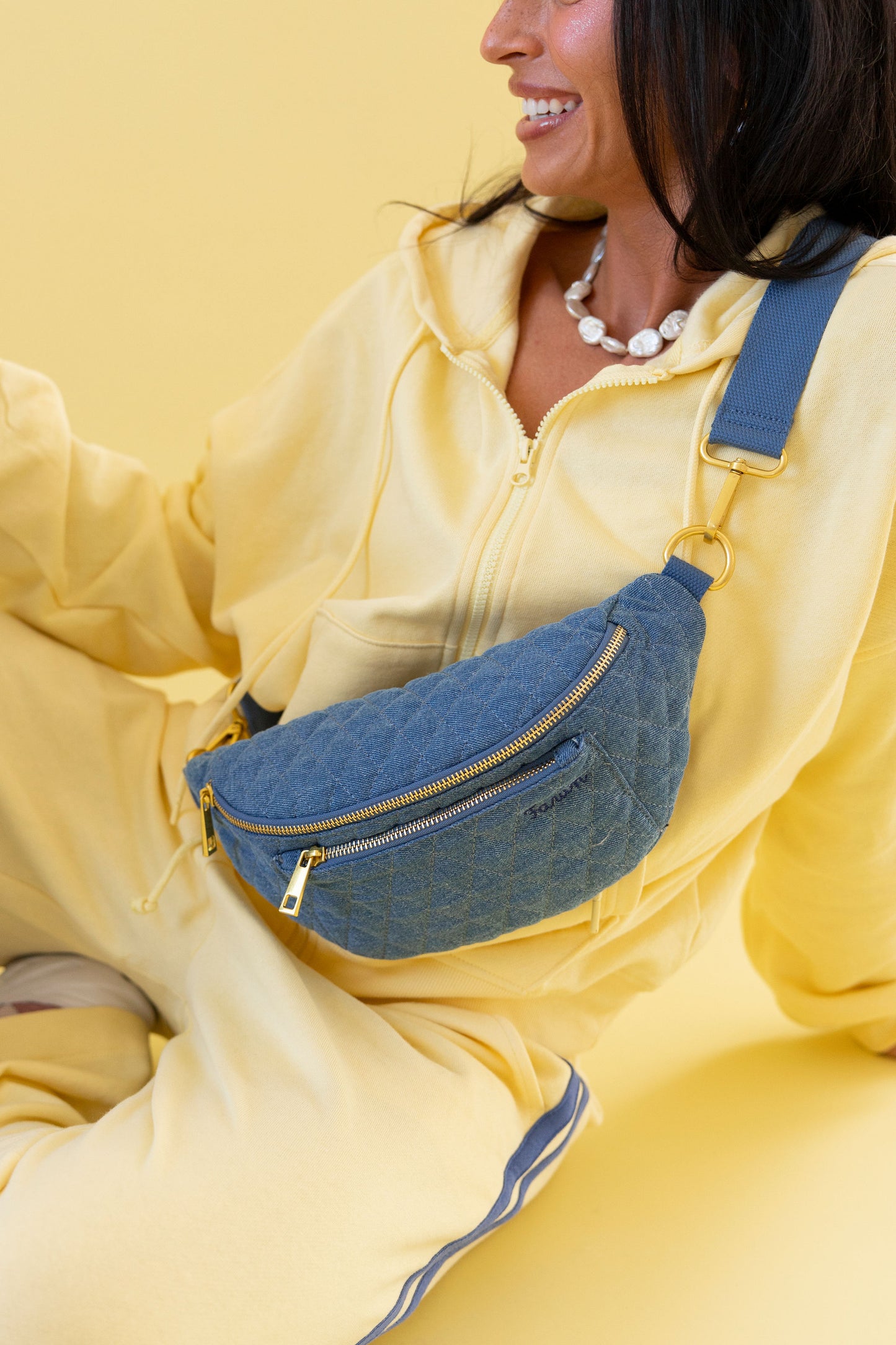 Person wearing a yellow outfit with a denim fawny pack against a yellow background