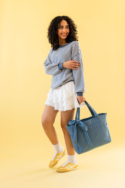Woman holding a denim quilted bag against a yellow background