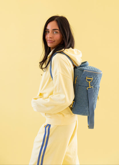 Woman in a yellow tracksuit with a blue backpack on a yellow background
