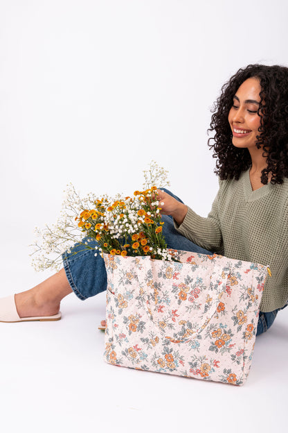 Woman holding a floral-patterned bag with flowers against a white background